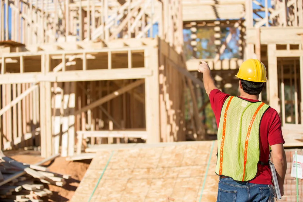 Worker in a high visibility vest pointing out framing on a building under construction