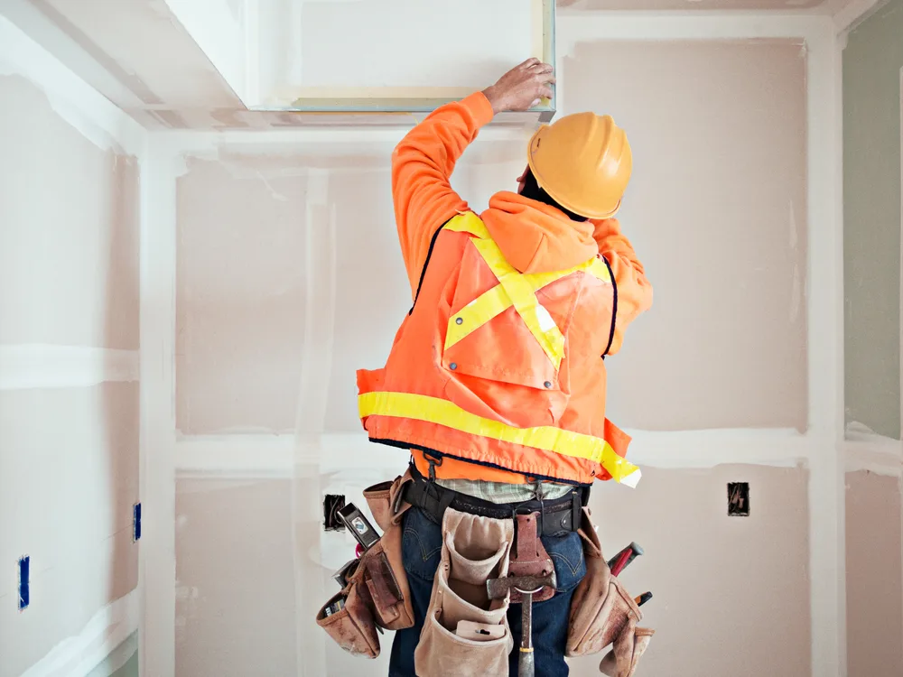 Construction worker in a high visibility vest working on drywall